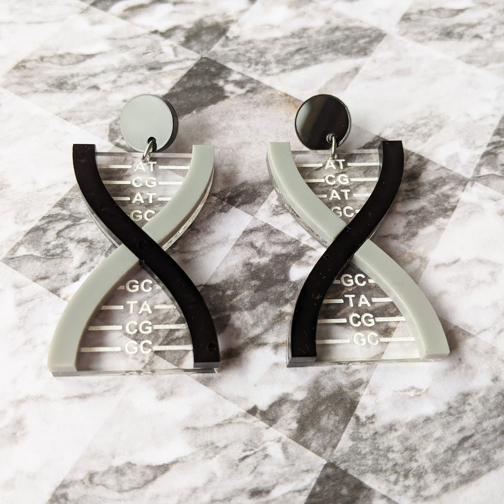 front view of a pair of DNA earrings in greyscale, handmade from laser cut acrylic.