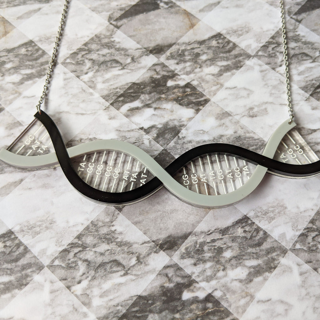 A DNA necklace, in greyscale, handmade from laser cut acrylic.