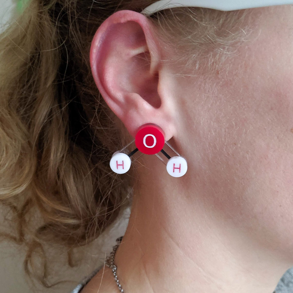 Laser Cut Acrylic Water Molecule Earrings. Ball and Stick Molecule with Oxygen and Hydrogen Atoms. Red and White Colourway. being modelled. 