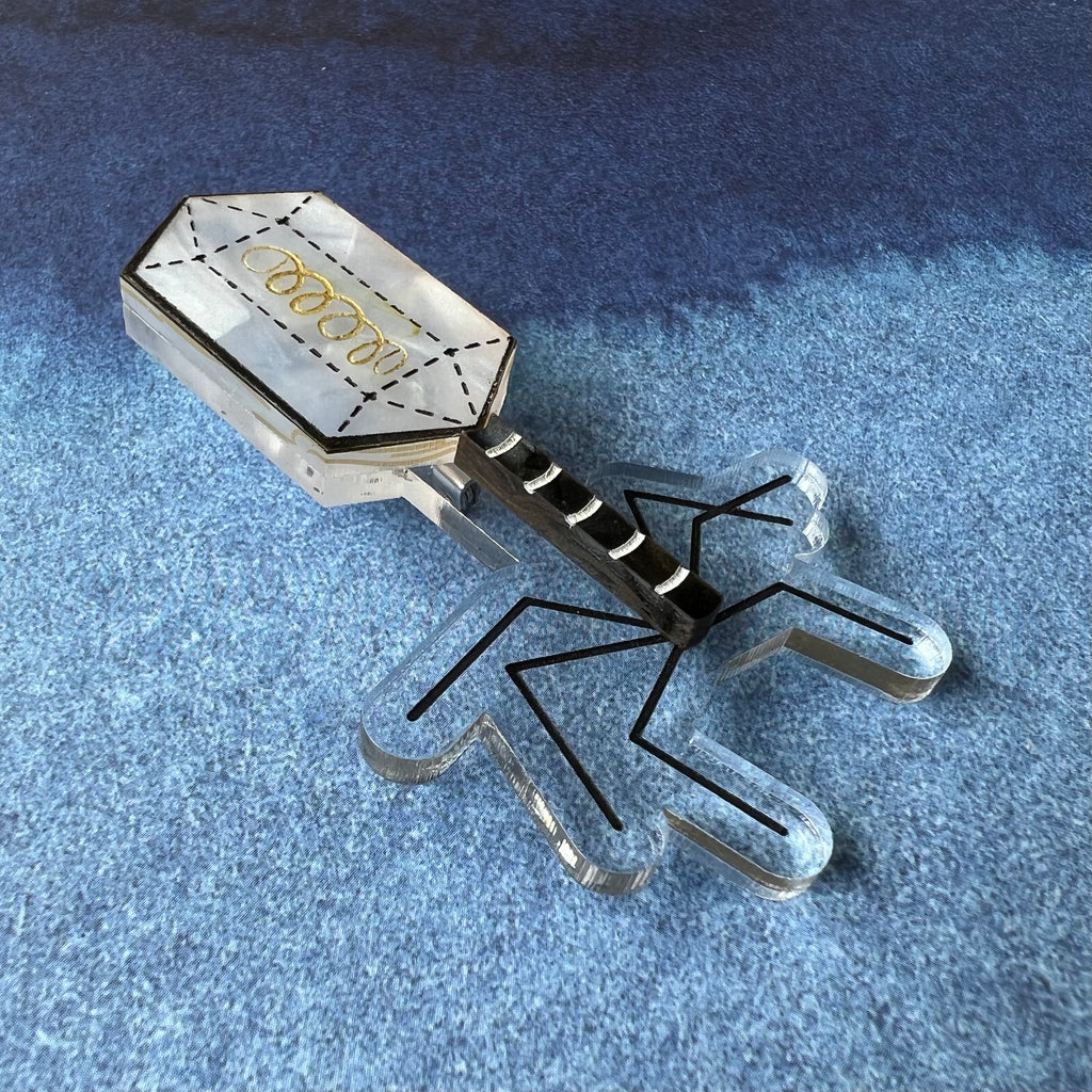 An angled view of a virus (bacteriophage) brooch, handmade from laser cut acrylic.