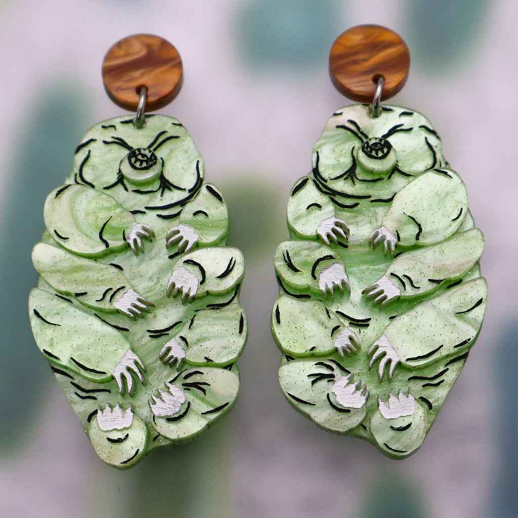 Green tardigrade earrings hanging from brown toppers. Made from laser cut acrylic.