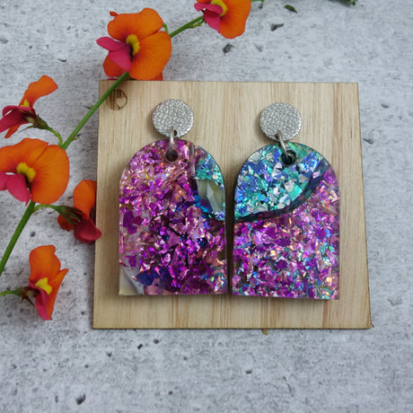 Arch shaped recycled acrylic earrings hanging from stainless steel toppers.