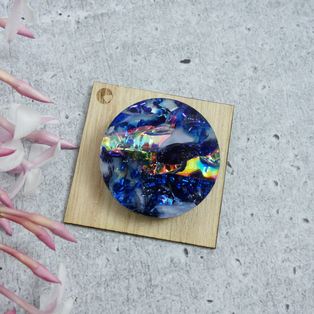 A round blue toned brooch made from melt pressed acrylic scraps.