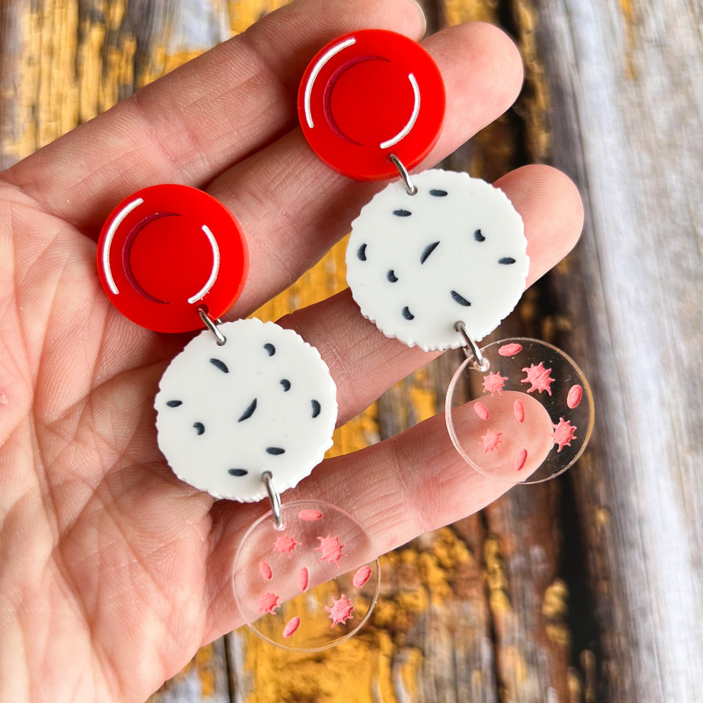 Dangle earrings comprising of a red blood cell topper, with a white blood cell and platelets dangling underneath. Laser cut and handpainted from acrylic. 