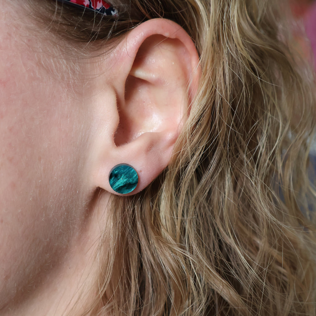 A small round green acrylic stud being modelled.