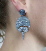 Laser cut acrylic horseshoe crab earrings, being modelled.