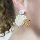 Laser cut acrylic hermit crab earrings, being modelled.