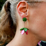 Close-up of a person wearing a green and pink floral earring.