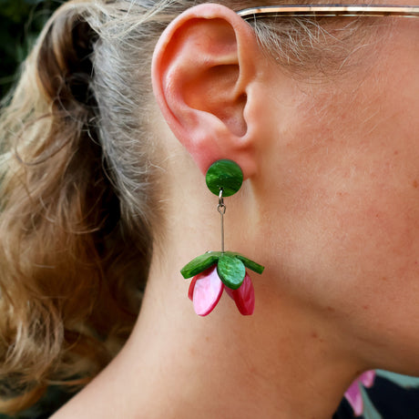 Close-up of a person wearing a green and pink floral earring.