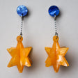 Pair of earrings with blue circular tops and yellow star-shaped drops on a light gray background