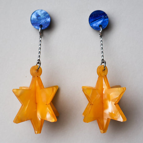 Pair of earrings with blue circular tops and yellow star-shaped drops on a light gray background