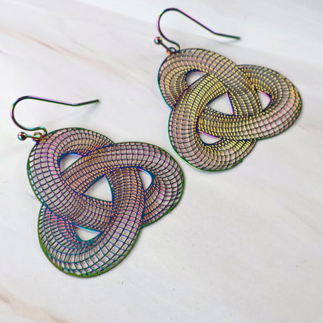 A pair of multicolored geometric patterned stainless steel earrings with rainbow metallic finish and french hooks, displayed on a white surface.
