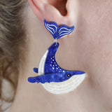 Laser cut acrylic humpback whale earrings being modelled.