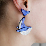 Laser cut acrylic humpback whale earrings being modelled.