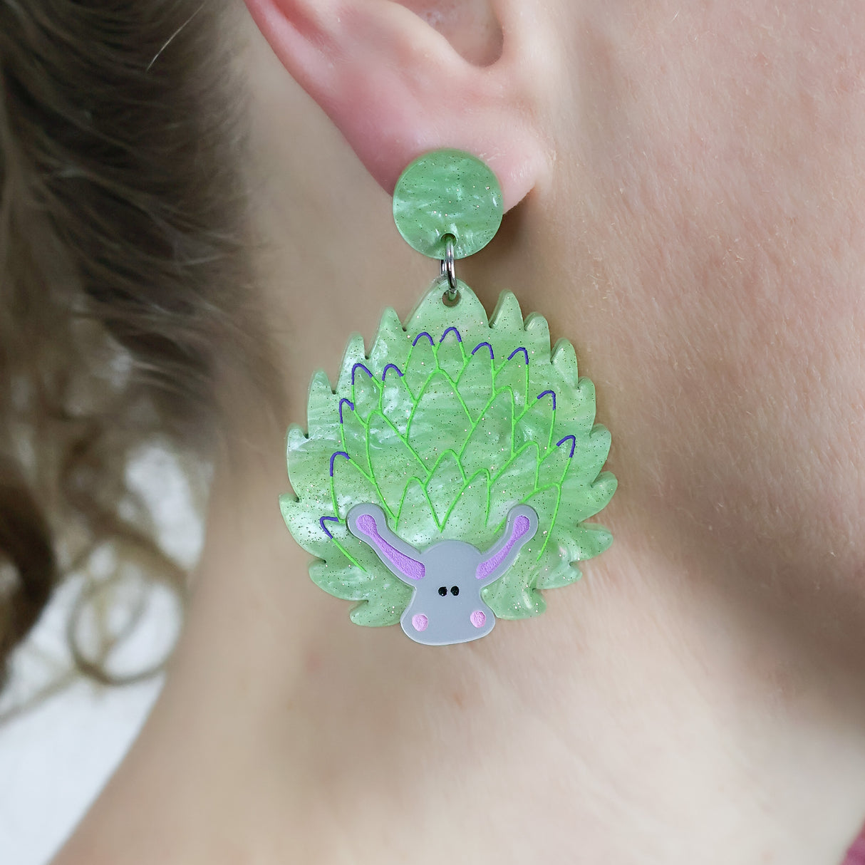 Laser cut acrylic leaf sheep earrings, being modelled.