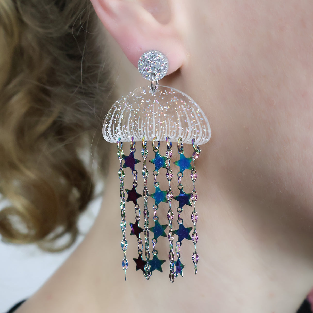 Acrylic jellyfish earrings with rainbow chain, being modelled. 