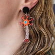 Laser cut acrylic neuron earrings being modelled. Earrings are cut from transparent acrylic, with the neuron design engraved and handpainted. The neurons hang from black earring toppers. 