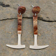 A pair of earrings designed to resemble fossil hammers with a silver pearlescent and brown swirly acrylic finish, attached to surgical steel posts with comfort clutch earring nuts. Laser cut acrylic.