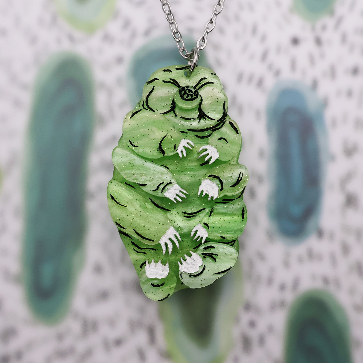 Front on view of green acrylic tardigrade pendant with stainless steel chain. 