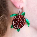 Acrylic turtle-shaped earrings worn by a person