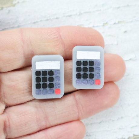 Small acrylic calculator studs being held in a hand