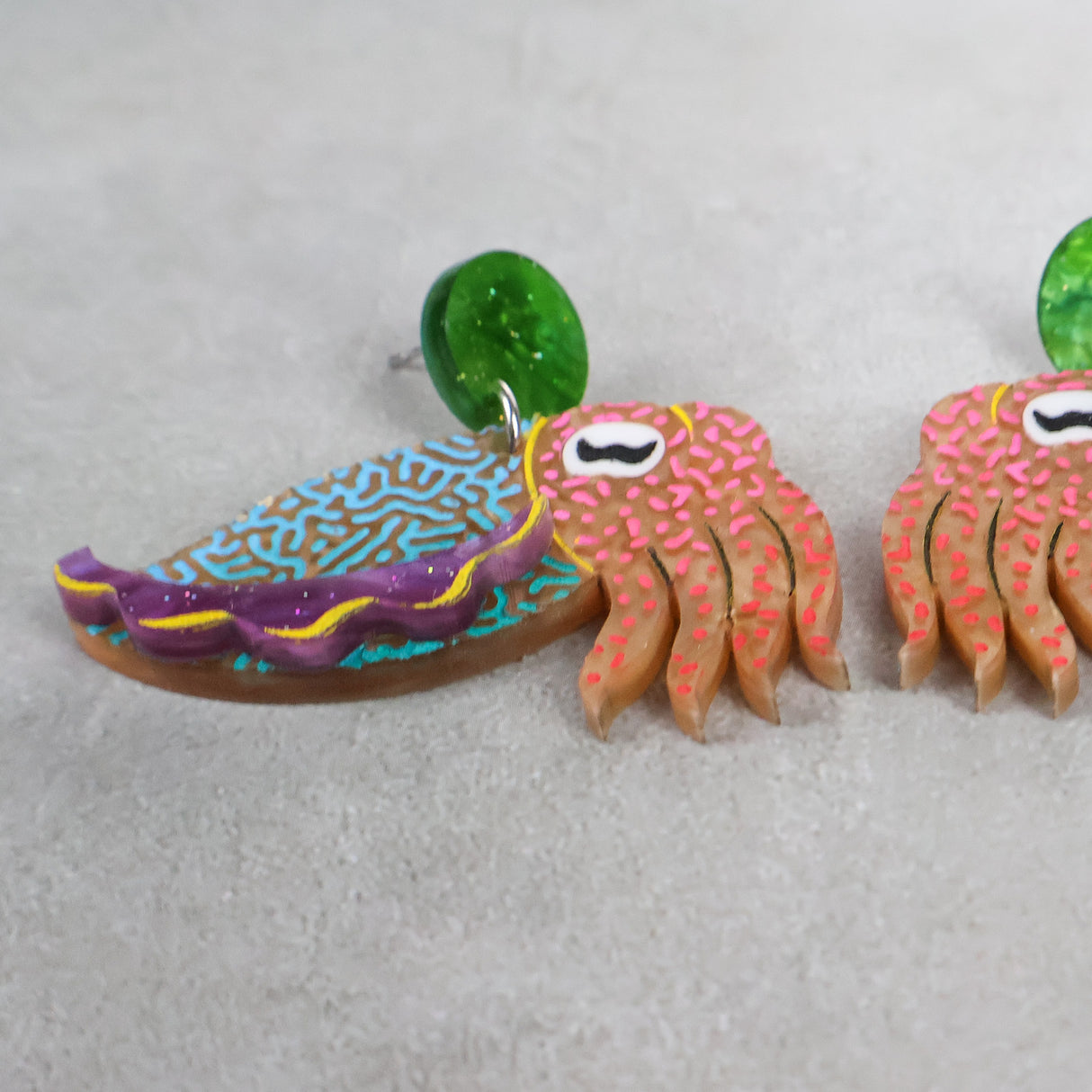 Closeup angled view of colorful acrylic cuttlefish-shaped earrings 