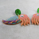 Closeup angled view of colorful acrylic cuttlefish-shaped earrings 