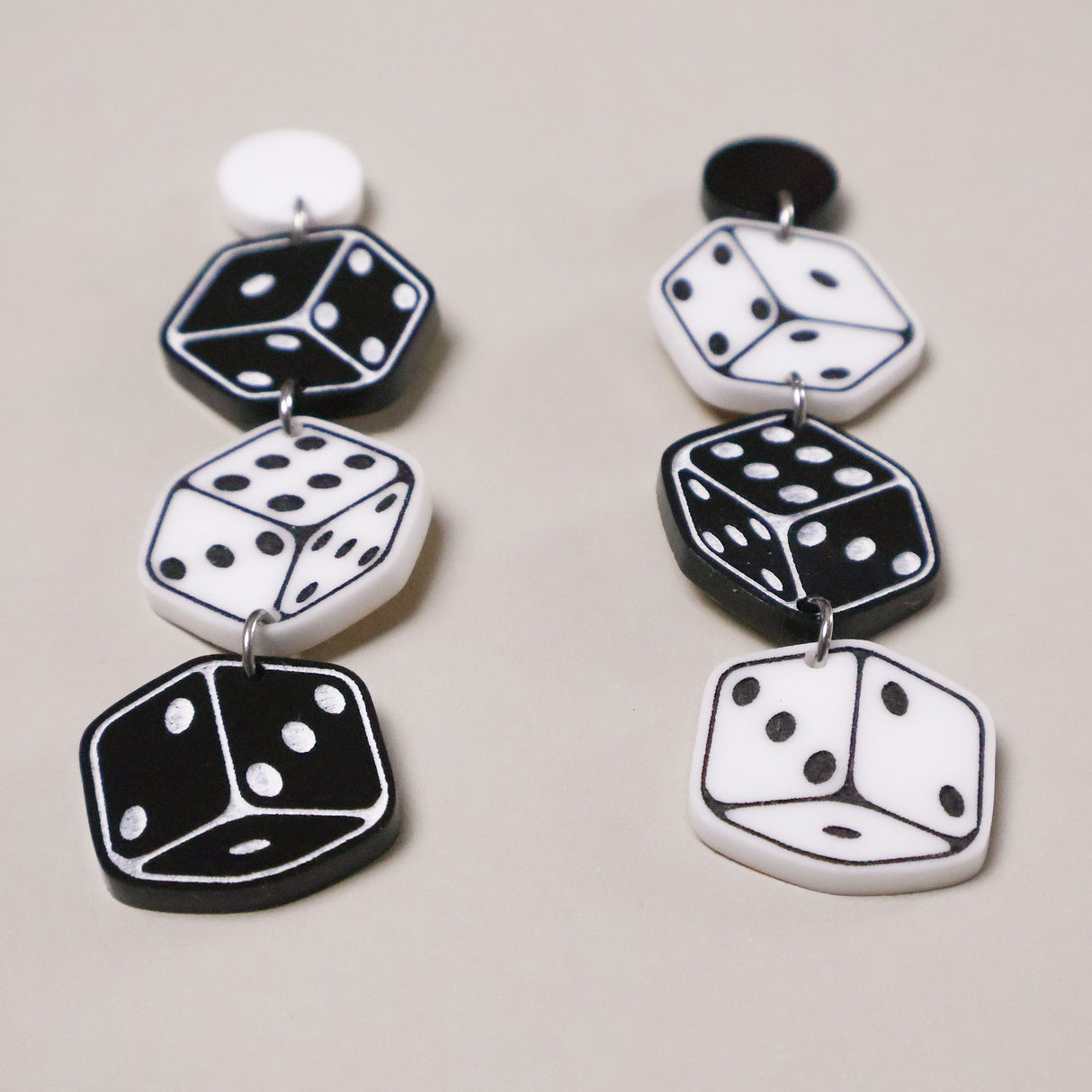 Pair of dice-shaped earrings on a light gray background