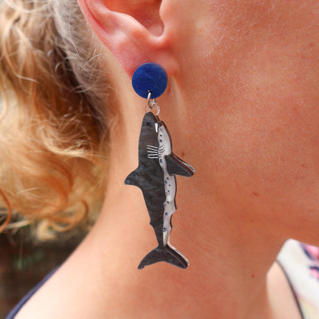 Salmon Shark-shaped acrylic earring worn by a person with blonde hair. Shark hangs from blue round earring topper. 