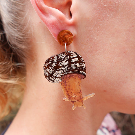 Acrylic snail earring being modelled by a blonde woman
