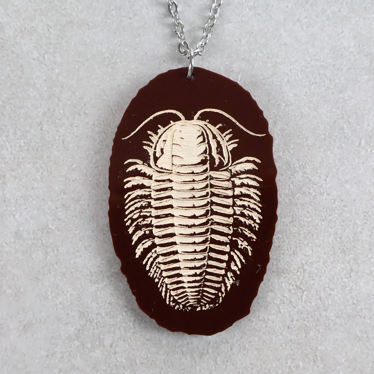 Brown acrylic pendant with trilobite design and stainless steel chain. 