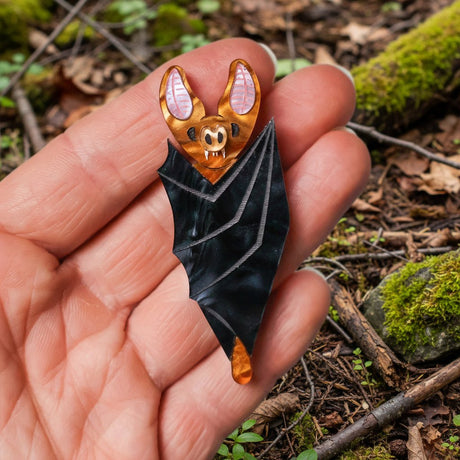 Small vampire bat acrylic brooch being held in a hand