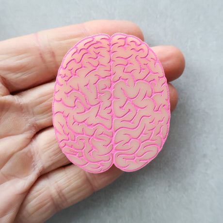 Pink brain-shaped brooch held in a hand
