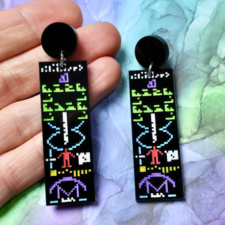 Arecibo message acrylic earrings being held up in a hand