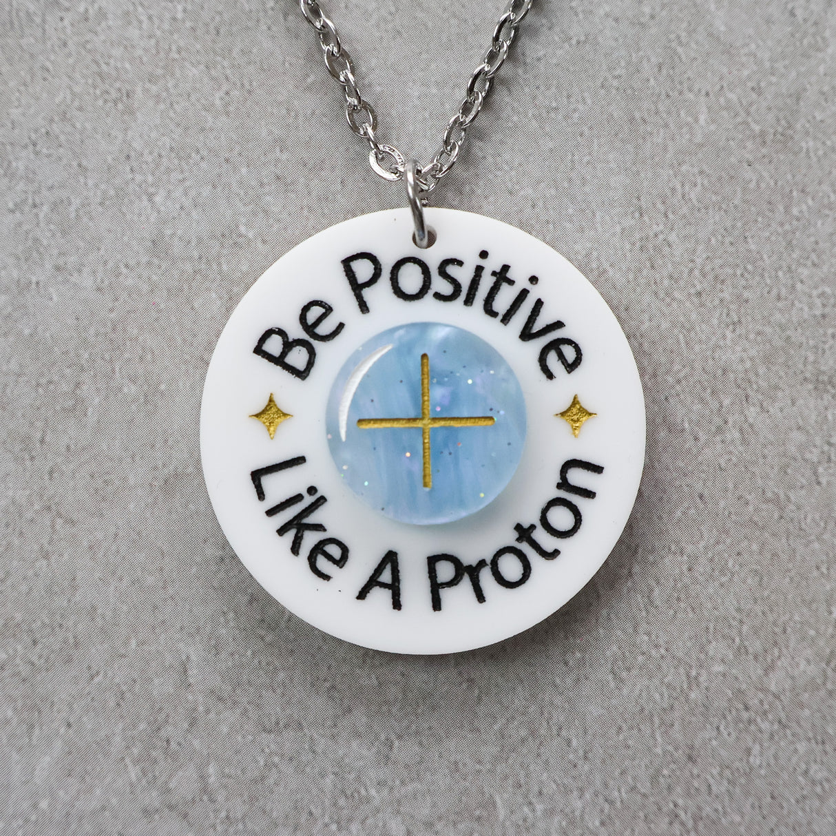 Necklace with a pendant that says 'Be Positive Like A Proton'