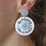 Earring with 'Be Positive Like A Proton' text worn by a person