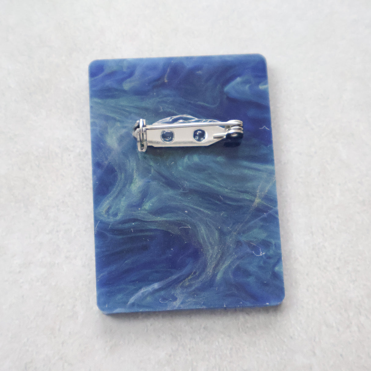 Back view of the binary code brooch showing stainless steel brooch pin and rolling clasp