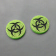 Small green glitter acrylic biohazard studs with black hand painted detailing. 