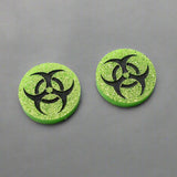 Small green glitter acrylic biohazard studs with black hand painted detailing. 