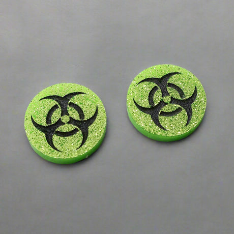 Small green glitter acrylic biohazard studs with black hand painted detailing. 