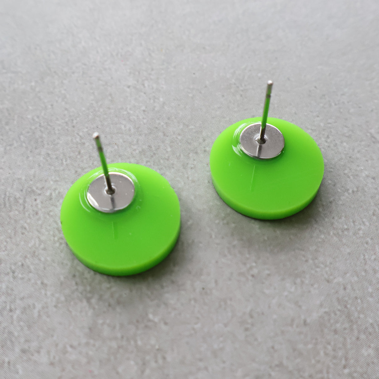 Back view of green biohazard studs showing stainless steel earring posts. 
