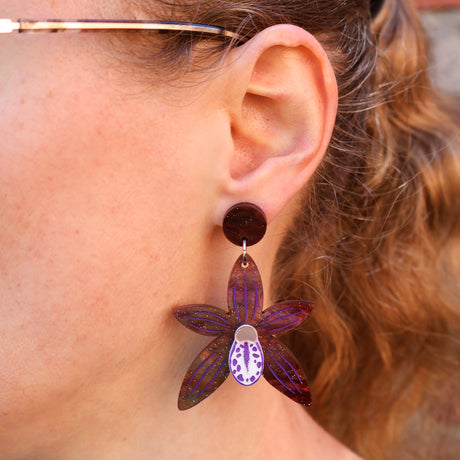 A woman modelling a pair of black orchid earrings