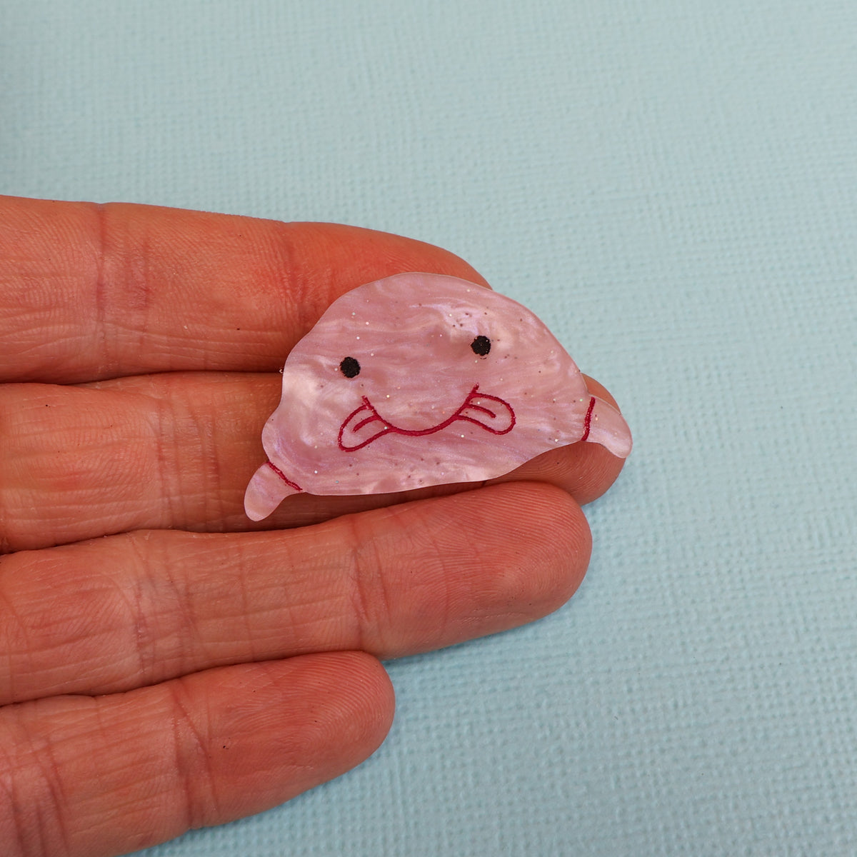 Closeup of acrylic Blobfish brooch in hand
