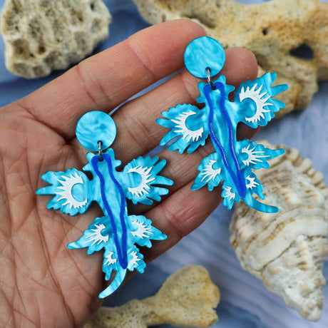 Laser cut acrylic blue sea dragon dangle earrings with matching round toppers. Held in hand.