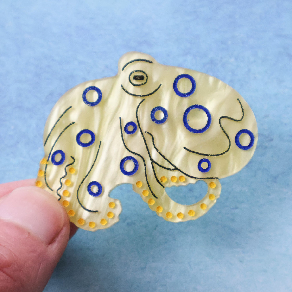 Blue ringed octopus acrylic brooch being held in a ahand