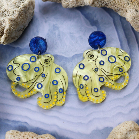 Laser cut acrylic blue ringed octopus dangle earrings, closeup with blue acrylic toppers. 
