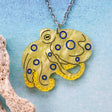 Yellow octopus pendant with blue accents on a chain against a light blue background