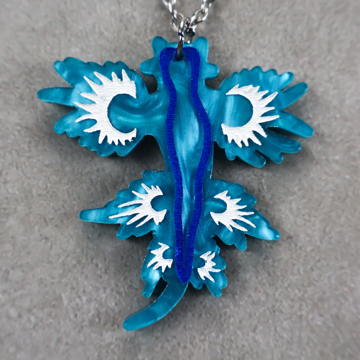 Blue and white sea dragon pendant on a gray background