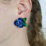 Close-up of an ear wearing blue and green blueberry earring.