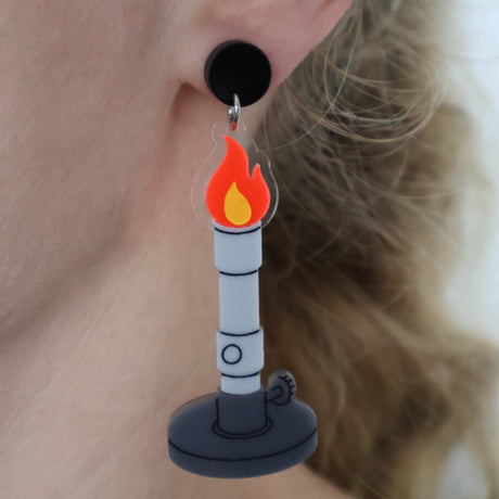 Bunsen burner acrylic earrings with red flame design modelled on an ear, with a black topper.